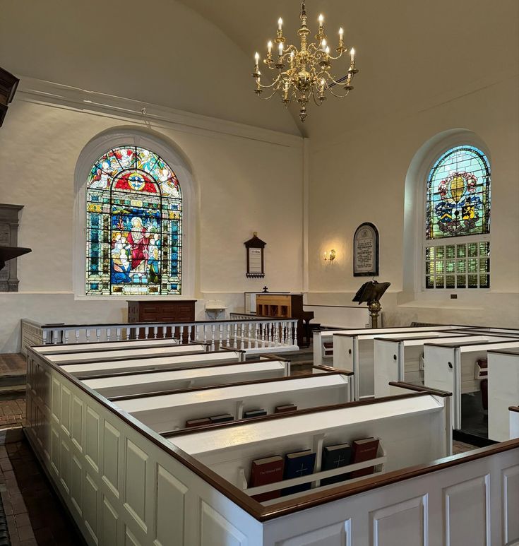 an empty church with stained glass windows and pews in the front, and a chandelier hanging from the ceiling