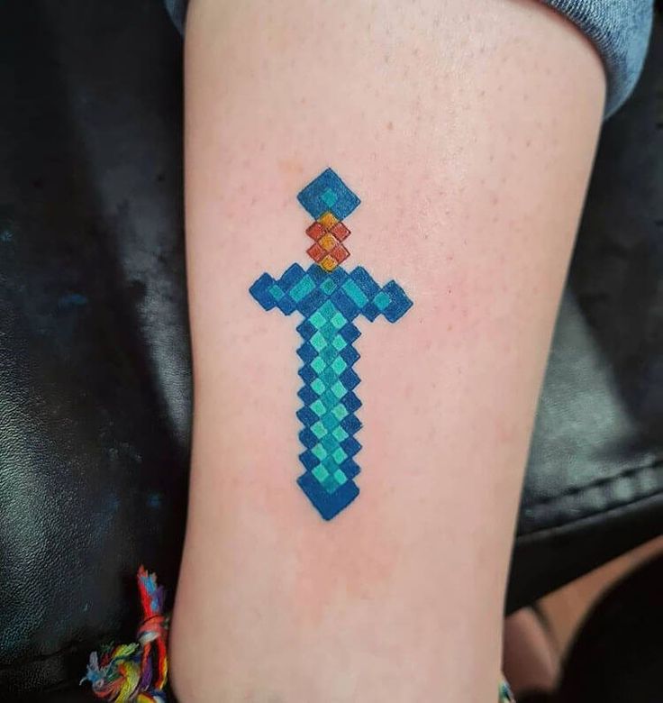 a cross tattoo on the leg of a woman's left arm, with an orange and blue design