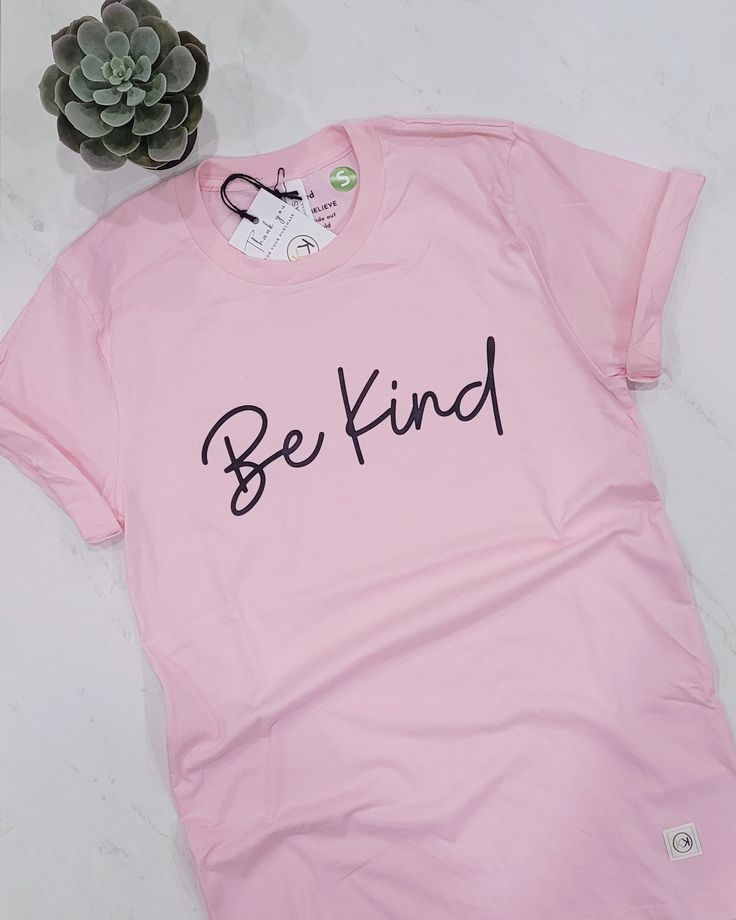 The pink 'Be Kind' t-shirt is a part of our Inspire Collection. It is a unisex classic fit, printed on a soft, ring spun cotton t-shirt. It features the classic script 'Be Kind' across the chest. Spread kindness with this casual staple, which is perfect for Pink Shirt Day Details: 100% ring spun cotton How this t-shirt fits: Fits true to size. Since it is a unisex classic fit, it can fit slightly loose and a little longer for women. Please refer to the sizing chart. How to care for your t-shirt: Machine wash in cold water, in a gentle cycle with like colours. Wash and iron garment inside out. Tumble dry on low Do not bleach Do not dry clean Do not iron over the design If unsure of sizes, please send us a message prior to placing your order. Pink Shirt Day, Positive Shirt, Inspirational Tees, Spread Kindness, Kindness Shirts, Inspirational Shirt, Soft Ring, Shirt Fits, Pink Shirt