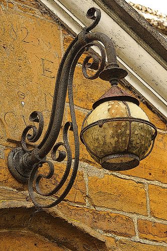 an old fashioned light hanging from the side of a building