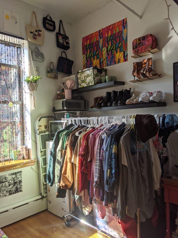 clothes are hanging on racks in a small room