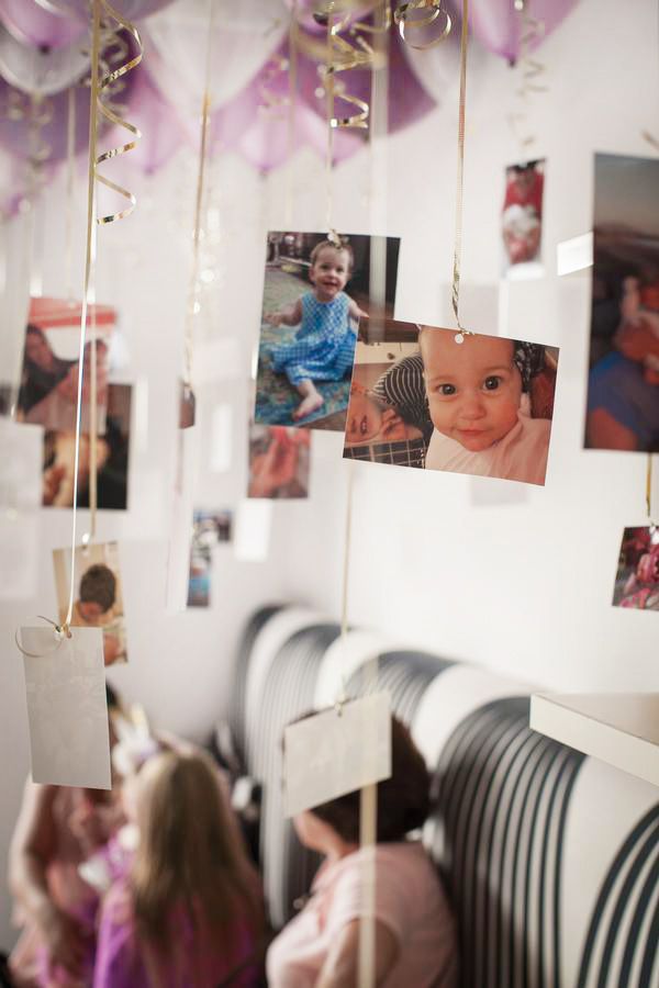 several pictures hanging from the ceiling in a room with balloons and streamers attached to it