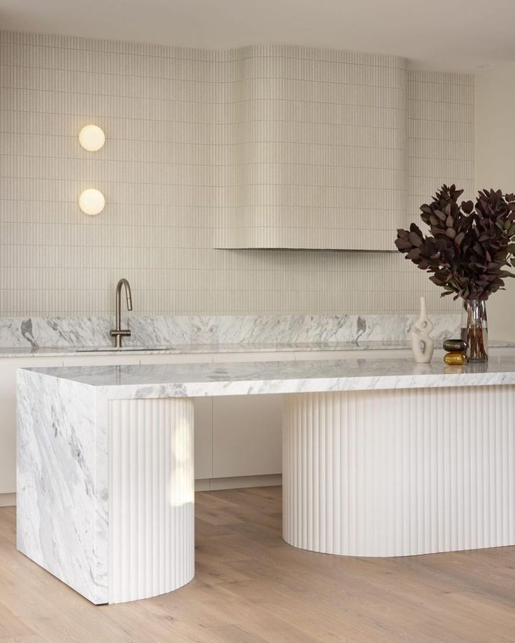 a kitchen with marble counter tops and white cabinets, along with an island style sink