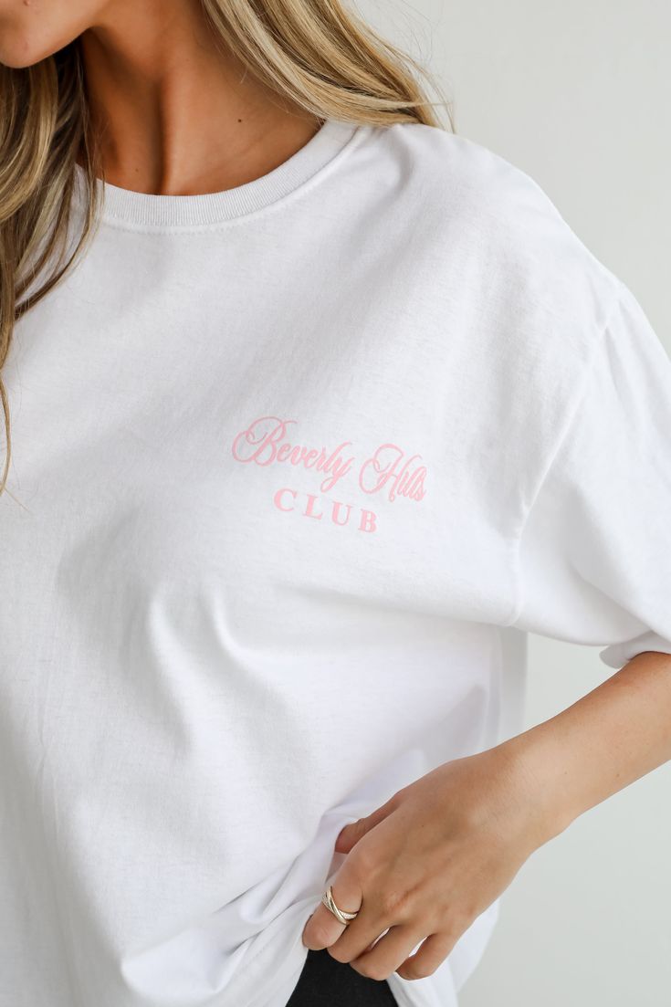 Showcase your love for sport and style with the Beverly Hills Tennis Club Graphic Tee! This chic and casual tee features a striking graphic that celebrates the elegance and excitement of tennis in the iconic Beverly Hills setting. Crafted from soft, high-quality cotton, this tee offers a comfortable, breathable fit that’s perfect for everyday wear. The classic crew neckline and short sleeves provide a relaxed silhouette that pairs effortlessly with jeans, shorts, or skirts. Whether you’re hittin Sporty White Slogan Top, Sporty White Top With Slogan, White Graphic Tennis T-shirt, Sporty White Graphic Print Tops, White Athleisure T-shirt For Spring, Spring Sports T-shirt With Text Print, Sporty White Print Short Sleeve Top, White Sporty T-shirt With Text Print, Spring Letter Print Athleisure T-shirt