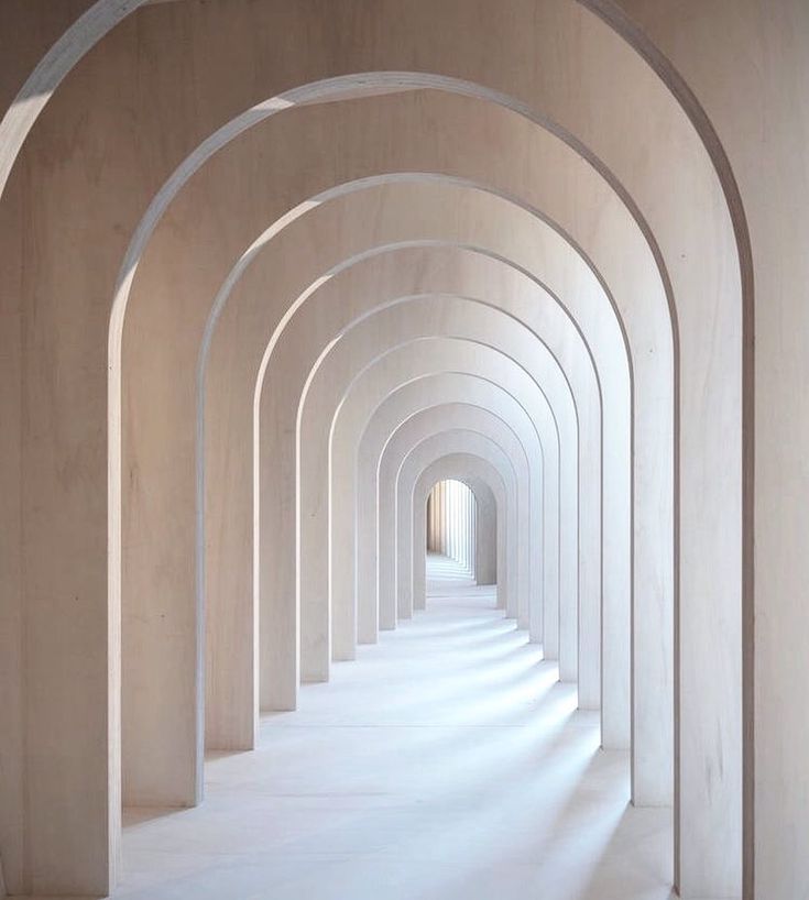 an arched hallway with white walls and columns