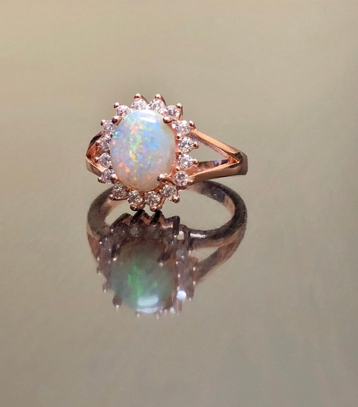 an opal and diamond ring on a reflective surface