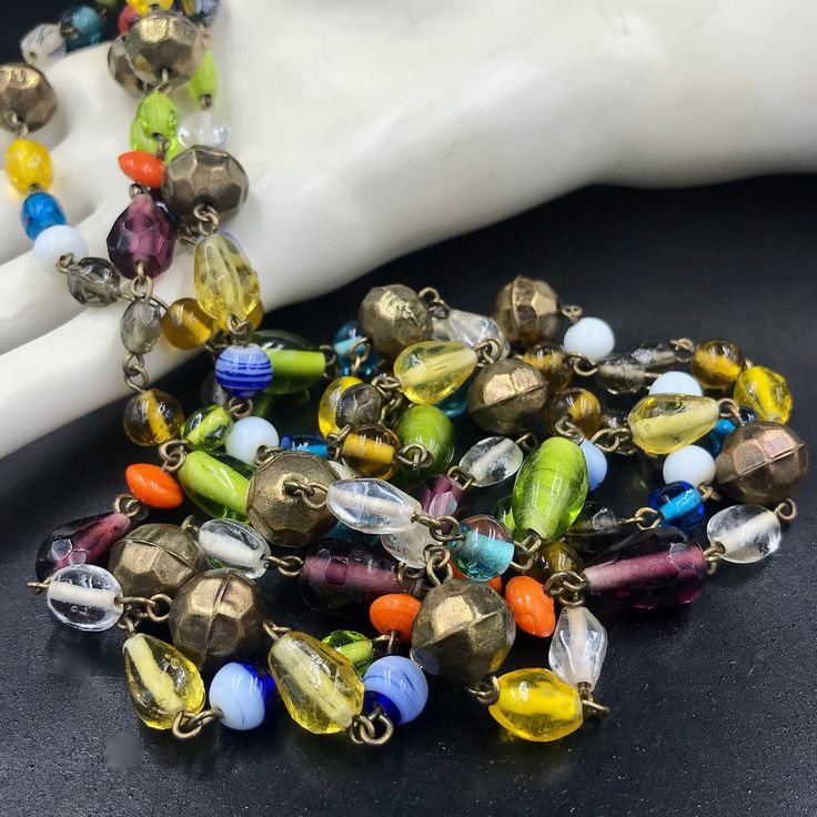 "This is one of my favorite types of necklaces to find. It's a LONG flapper style - over the head with no fastener/clasp - necklace made from SMALL wired art glass beads. The multi-colored beads are lovely with some being more \"solid\" in terms of color and others being more \"clear\" or \"transparent.\" The different shaped beads are wired together. There are 12 orb shaped brass beads evenly interspersed among the glass beads. I think the necklace is most likely a 1970s reproduction rather than a true 1920s/1930s flapper era necklace. For this reason, I was hesitant to date it but know it to be vintage by Etsy's standards. The beads could be Czech glass or even made in Japan. The necklace can be worn long or doubled. It has a HANG length of 29 inches. The width of the necklace varies wit Vintage Multicolor Multi-strand Beads, Vintage Adjustable Multicolor Necklaces, Vintage Multicolor Beaded Jewelry, Retro Beaded Jewelry For Gifts, Retro Beaded Jewelry As Gift, Retro Beaded Jewelry Gift, Vintage Multi-strand Beaded Necklace With Colorful Beads, Vintage Multi-strand Colorful Beaded Necklaces, Vintage Multi-strand Beaded Necklaces With Colorful Beads