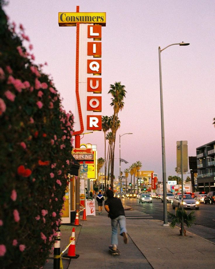 a man walking down a sidewalk next to a tall sign that reads, consumer liquor