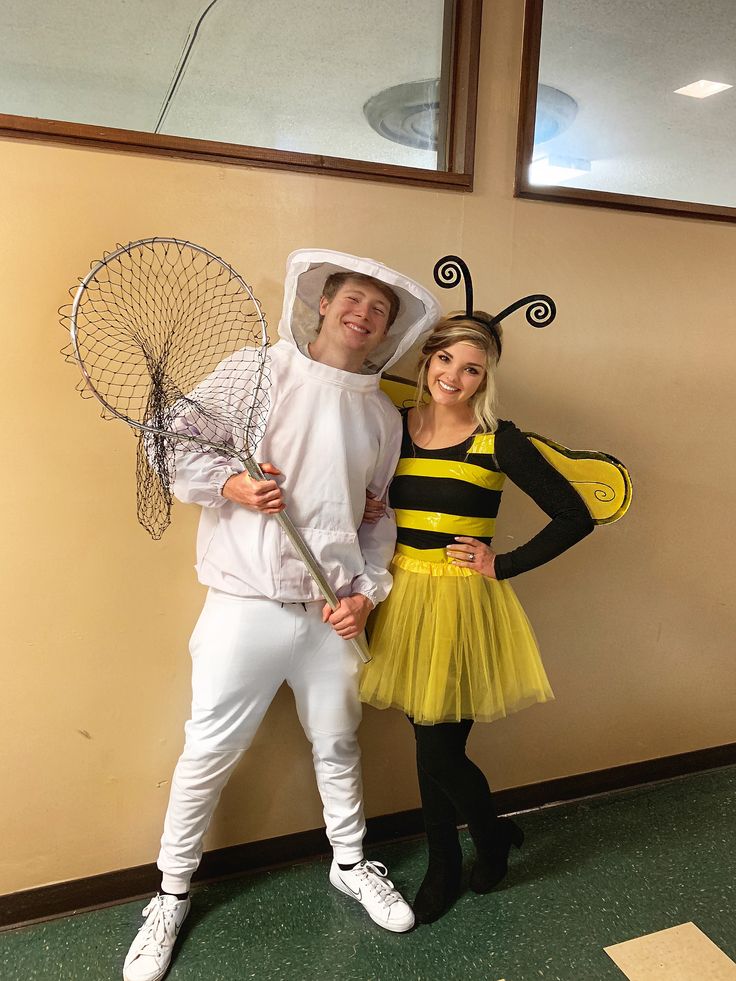 two people dressed up in costumes posing for the camera with one holding a badminton racket and the other wearing a bee costume