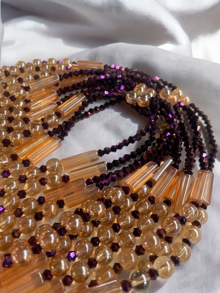 Why You'll Love It: Striking Design: The rich purple crystal glass beads paired with the warm golden sandy brown accents create a luxurious and timeless aesthetic. Premium Quality: Crafted with high-quality glass beads, ensuring durability and lasting brilliance. Comfortable Fit: The elastic design offers a comfortable and flexible fit for all-day wear. Versatile Style: Perfect for everyday wear, special occasions, or as a thoughtful gift. Cultural Significance: Purple: In Ivorian culture, purpl Brown Beaded Necklaces With Round Beads For Party, Brown Faceted Beads Jewelry For Party, Brown Beaded Necklaces For Parties With Polished Beads, Brown Beaded Necklaces With Colorful Beads For Parties, Brown Polished Beads Necklace For Party, Brown Gold Beads Jewelry For Party, Brown Faceted Beads Necklace For Party, Adjustable Brown Beads For Party, Brown Beaded Necklaces With Large Beads For Party