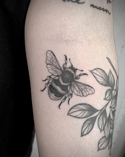 a black and white photo of a bee with leaves on it's back leg