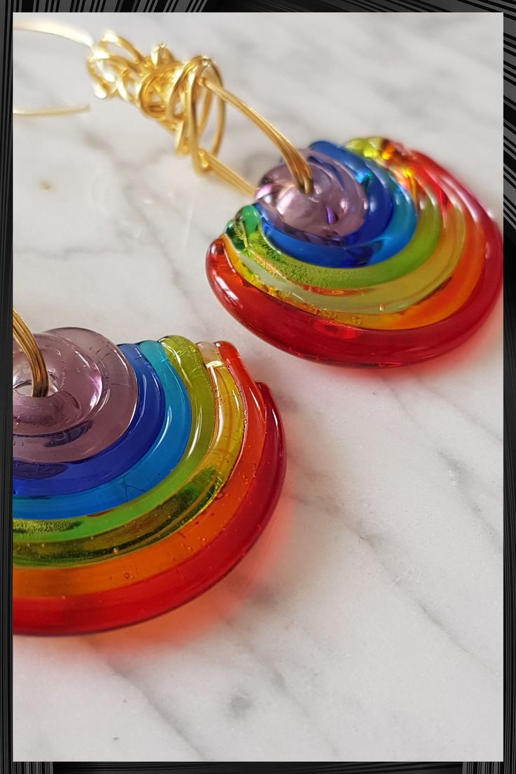 a pair of rainbow colored earrings on a marble surface