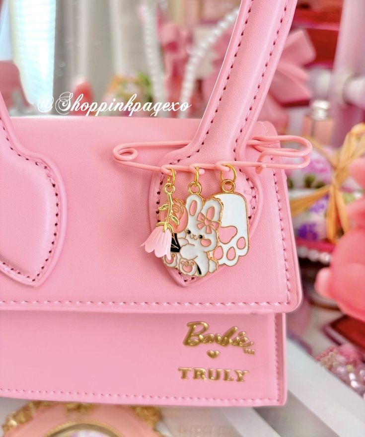 a pink handbag with hello kitty charms on it