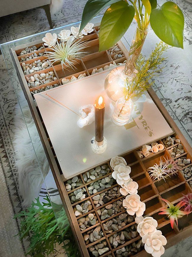 a glass table with plants and candles on it