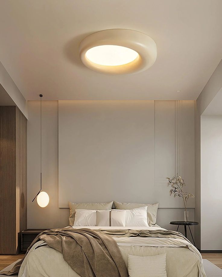 a large bed sitting under a round light in a bedroom next to a wall mounted lamp