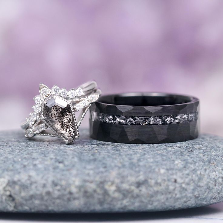 two wedding rings sitting on top of a rock next to each other with diamonds in them