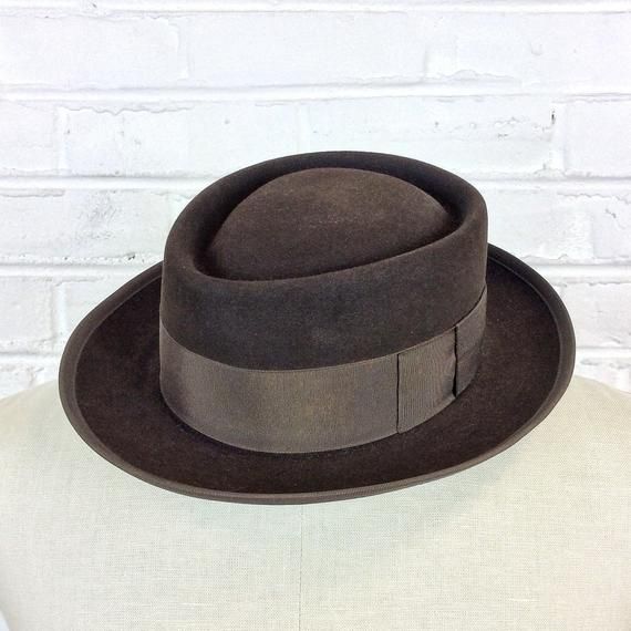 Size 6 7/8 Vintage 1950s 1960s Adam Hats Carbon Brown Porkpie Fedora Hat For your consideration we have a vintage fedora from the ‘50s/‘60s. Made by Adam Hats from a “carbon brown” fur felt, this “Rugby” model features a telescopic crown, brown grosgrain band and edge, leather sweatband, and rayon lining. There are a few spots on the hat band and a few stitches have come out of the leather sweatband. This is still a great hat and wonderful for anyone into slick bop midcentury style.Measurements; Retro Curved Brim Felt Hat For Winter, Classic Brown Boater Hat With Flat Brim, Retro Winter Fedora With Flat Brim, Retro Flat Brim Fedora For Winter, Retro Winter Fedora With Curved Brim, Winter Retro Adjustable Fedora, Brown Felt Hat With Flat Bill For Formal Occasions, Fitted Brown Boater Hat With Flat Brim, Brown Fitted Boater Hat With Flat Brim