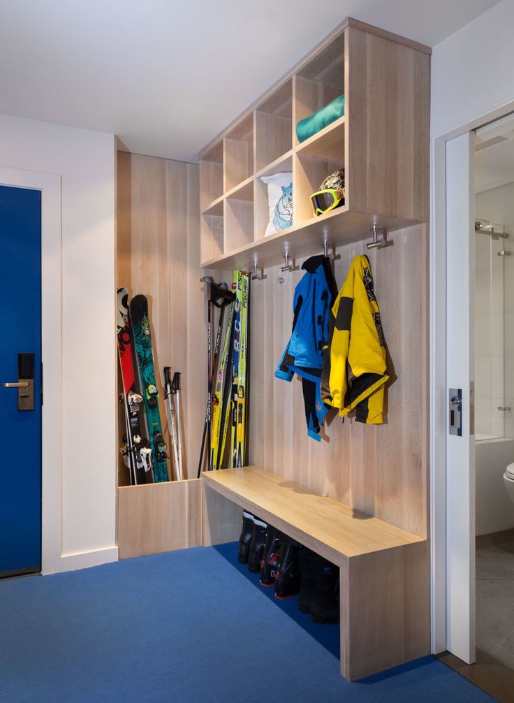 a coat rack filled with skis and snowboards next to a blue toilet in a bathroom