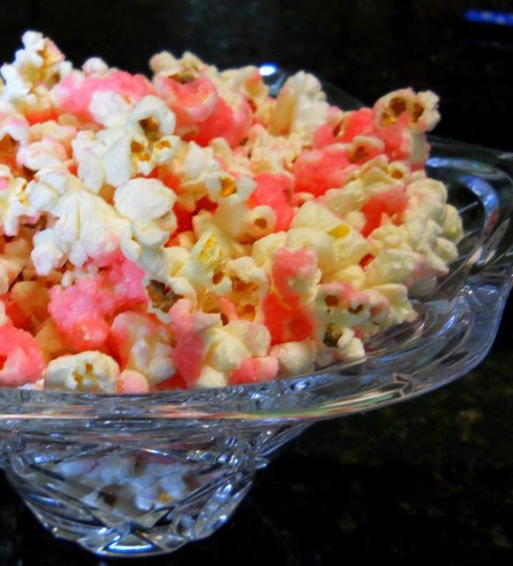 a glass bowl filled with pink and white popcorn