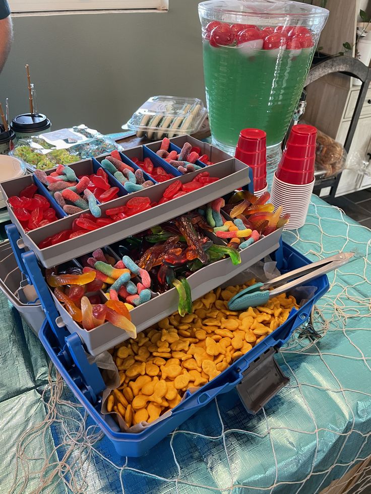 there are many different types of candy in the trays on the table with drinks