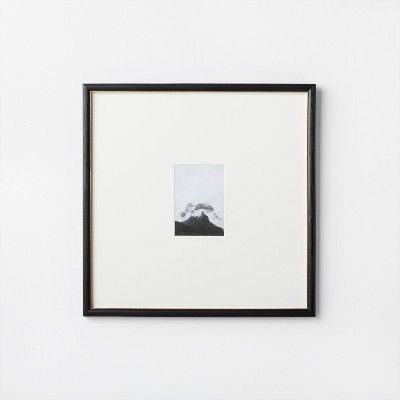 a black and white photo hanging on the wall next to a framed art piece with a mountain in the background