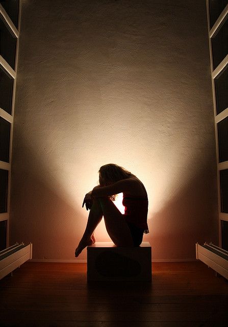 black and white photograph of a woman sitting in front of a light on the floor