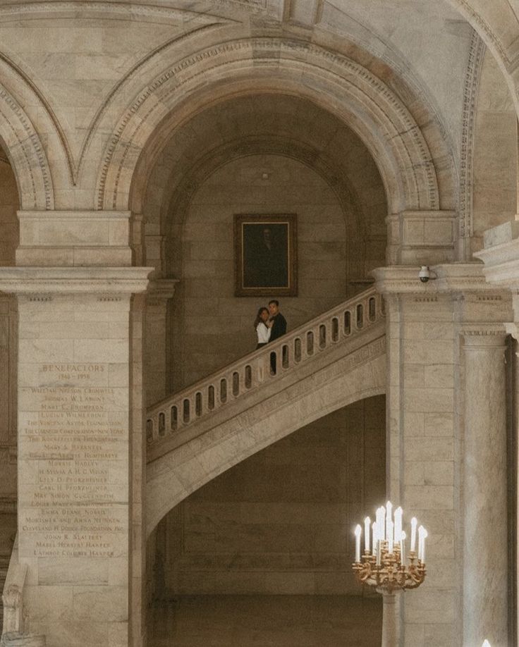 an ornate staircase with chandelier and paintings on the walls in a large building