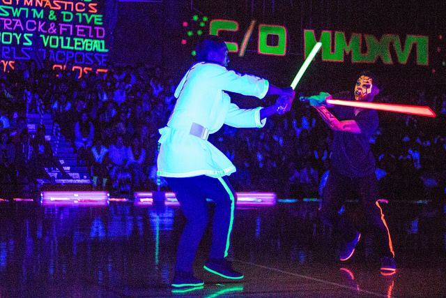 two people in costume are playing with lightsticks on a stage while an audience watches