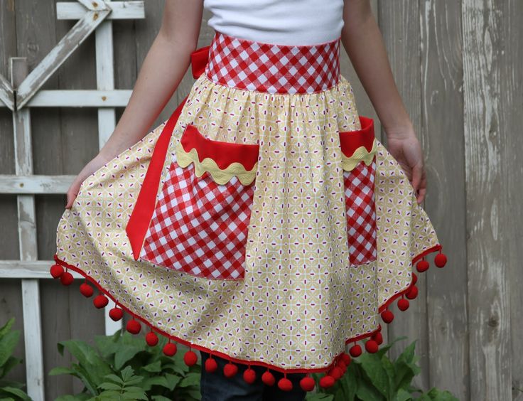 a woman wearing a red and white apron with pom - poms on it