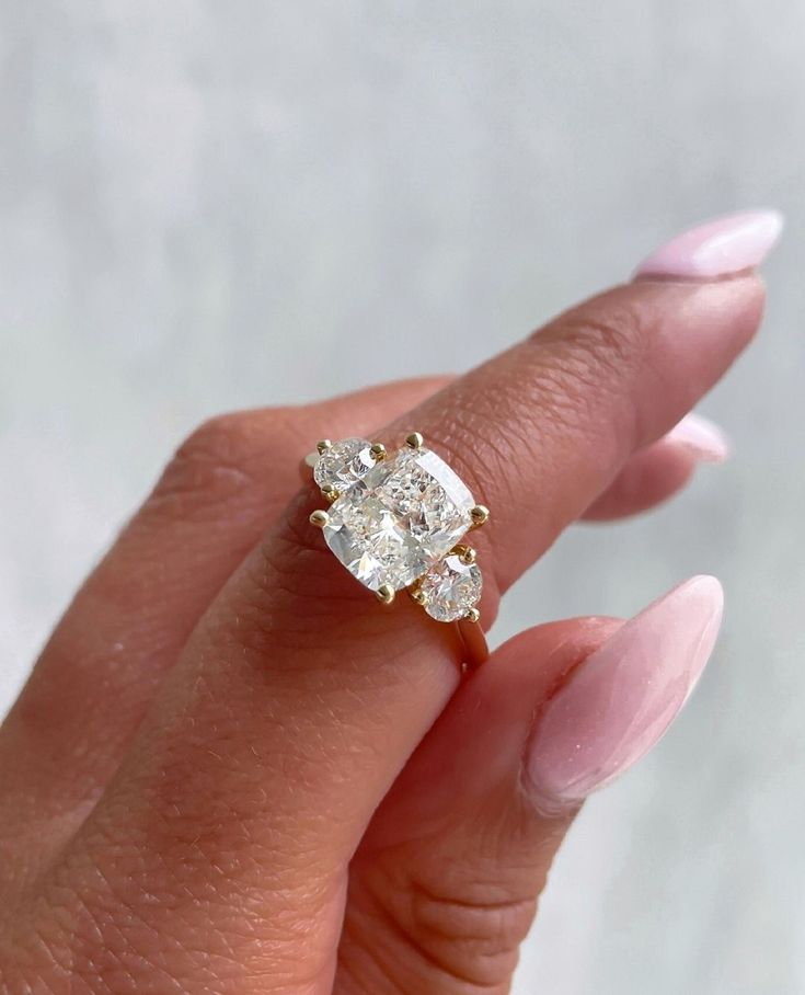 a woman's hand holding an engagement ring with two diamonds on it and the middle finger