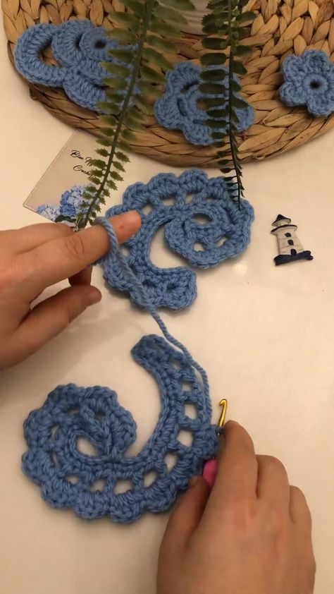 someone is crocheting some blue flowers on a table