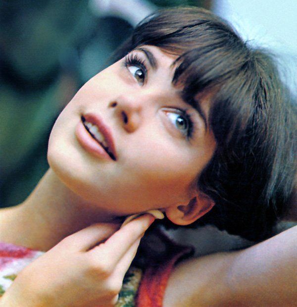 a young woman poses with her hand on her chin and looking up at the sky