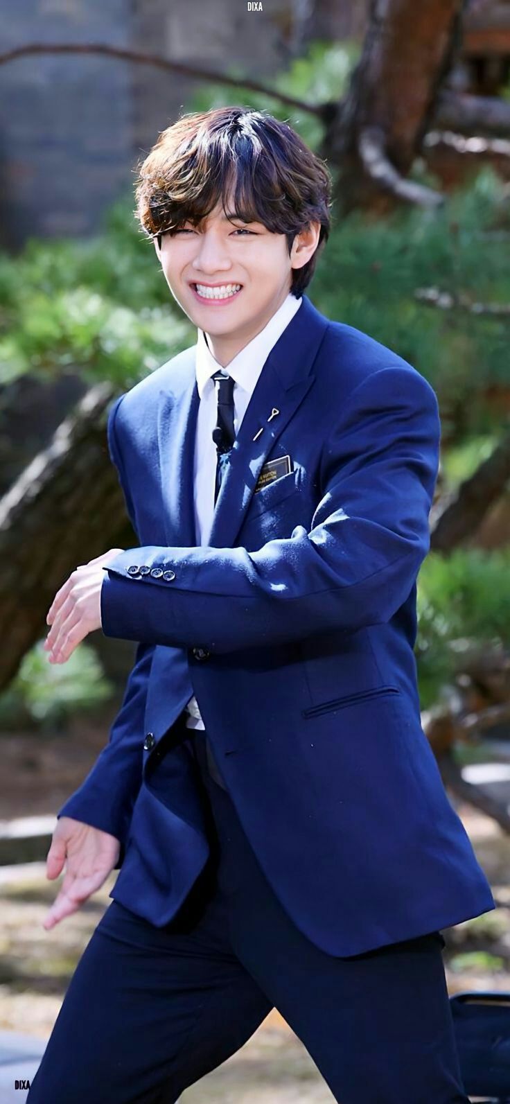 a young man in a suit and tie is posing for a photo with his arms crossed