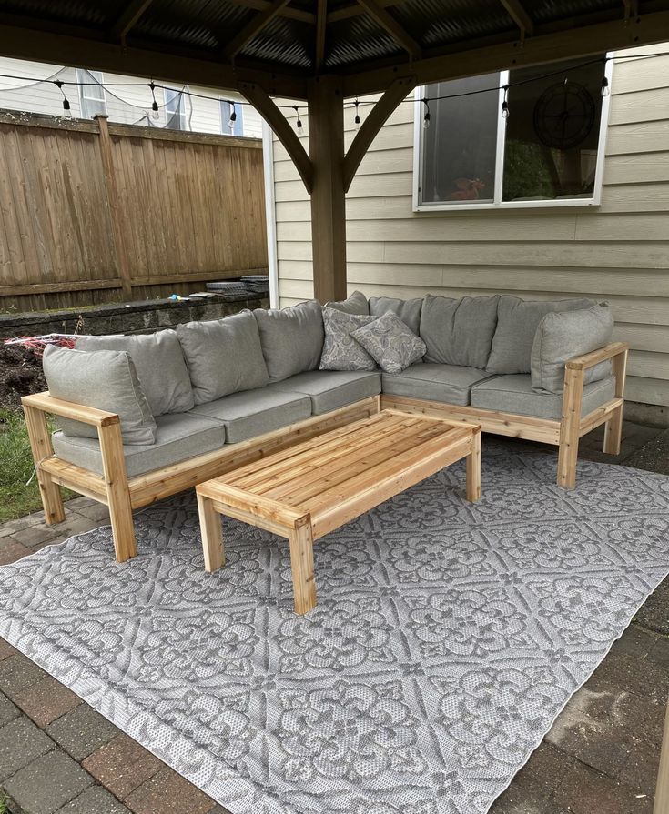 a couch and coffee table sitting on top of a rug in front of a house