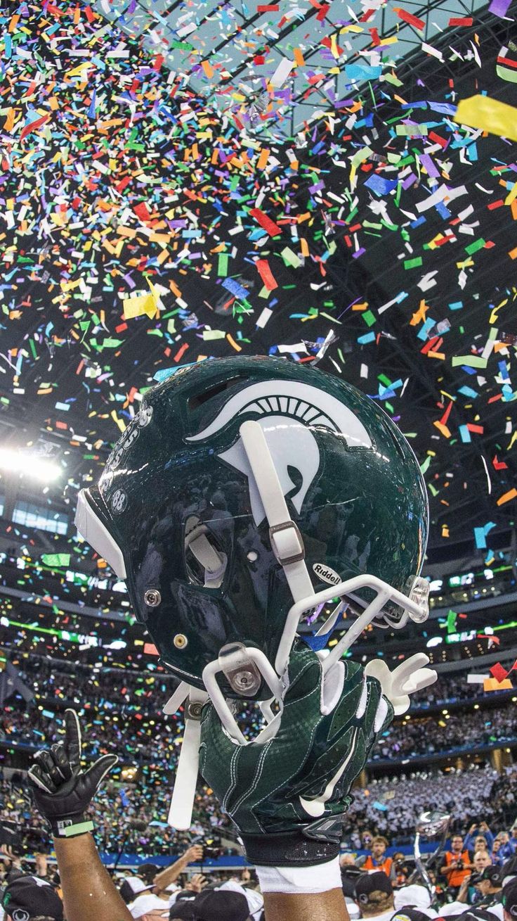 a football helmet is held up in the air with confetti all around it