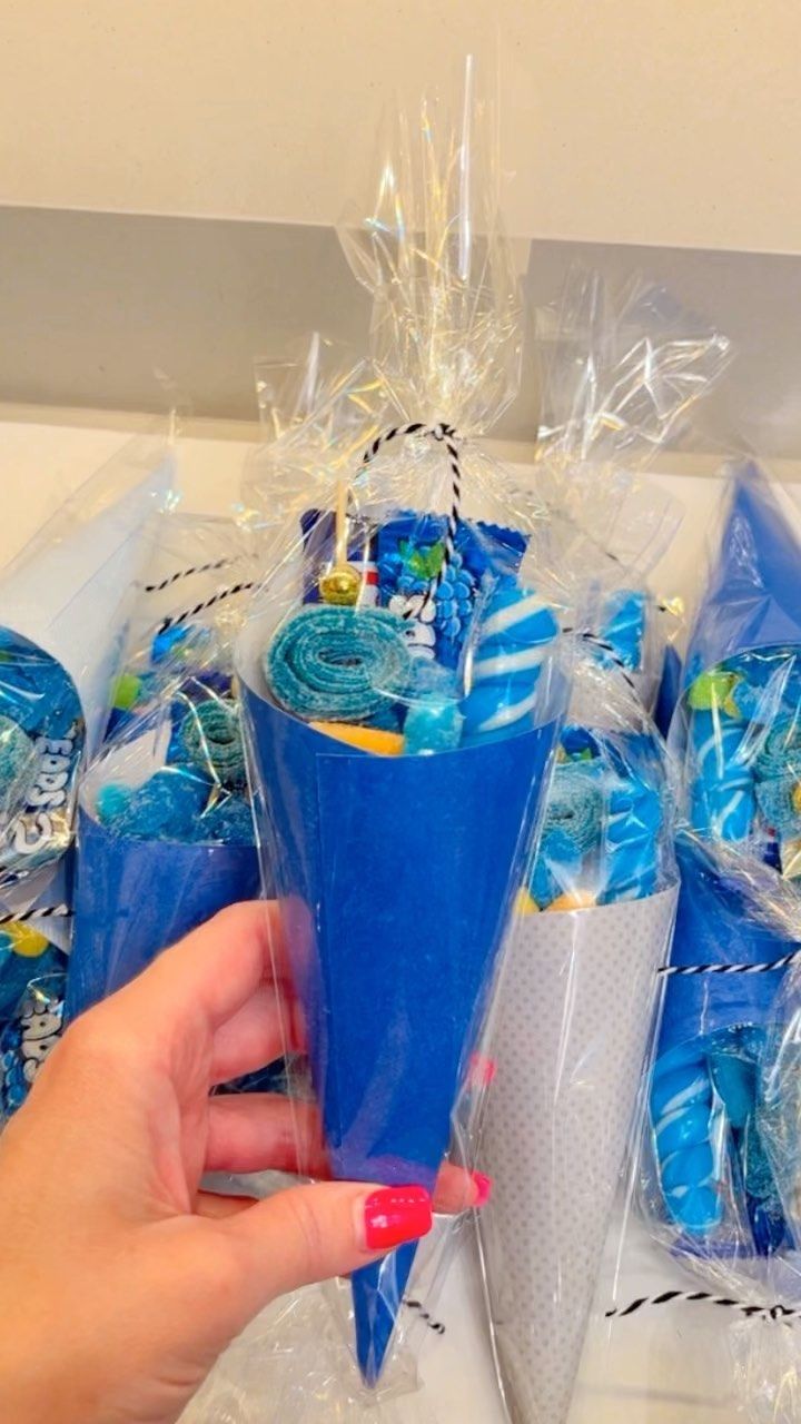 a person is holding a blue cup with candy in it and wrapped in plastic bags