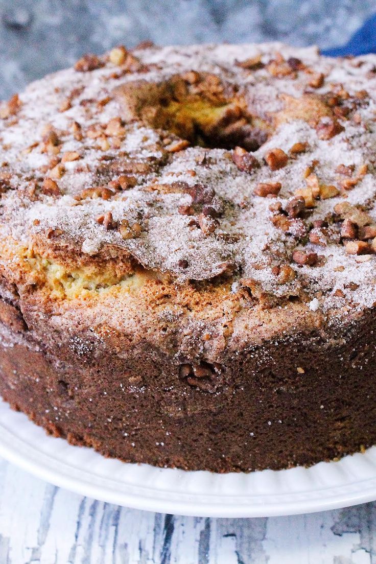 a chocolate cake on a white plate with powdered sugar and walnuts around it