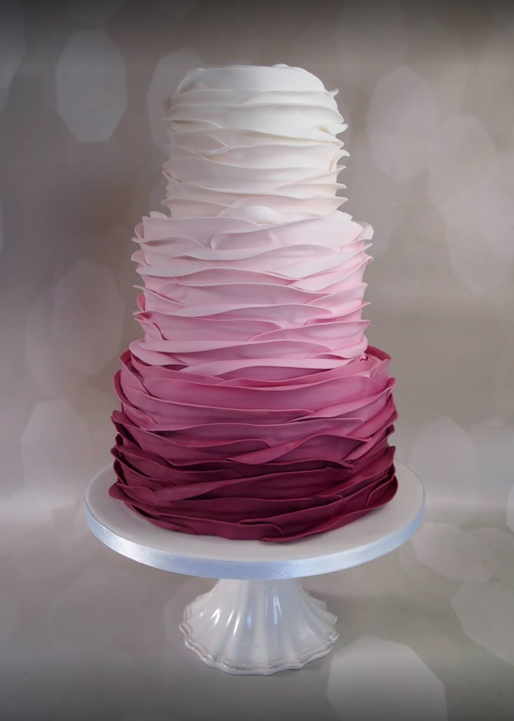 a multi - layered cake with white, pink and purple icing on a pedestal