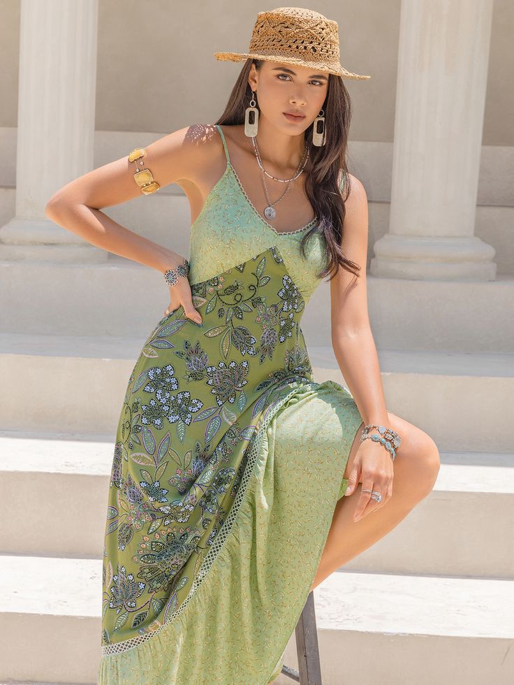 a woman in a green dress and straw hat poses for the camera while leaning on a chair