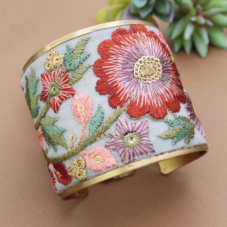 Vintage inspired hand embordered beauty! This gold cuff bracelet features intricate white fabric embroidered with vibrant rust, rose, and pink flowers. Add a blend of elegance and bohemian charm to your look.  * Handmade  * Gold cuff bracelet with pink floral embroidery  * Fabric design varies by bracelet. I also have the matching earrings in my shop * Floral embroidered fabric  * Brushed gold metal * Handmade Measurements (approx.)1 5/8" wide Spring Bohemian Cuff Bracelet, Bohemian Cuff Bracelet For Spring, Bohemian Cuff Bracelets For Spring, Multicolor Embroidered Bangle Jewelry, Bohemian Embroidered Cuff Bracelet As Gift, Bohemian Embroidered Bracelets For Weddings, Bohemian Embroidered Cuff Bracelet For Gift, Gold Embroidered Bracelets For Wedding, Bohemian Embroidered Bangle Bracelets