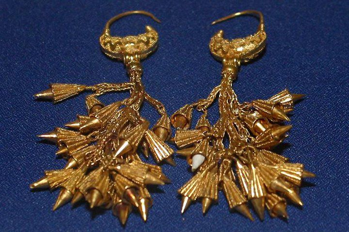 two pairs of gold tone earrings on a blue background