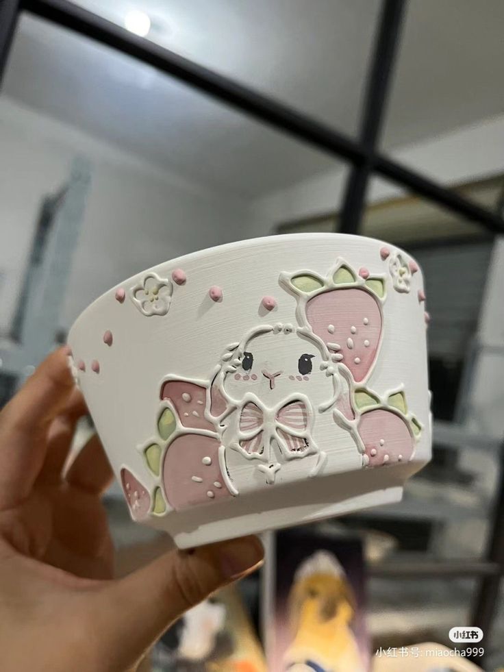 a hand holding up a white box with pink and green designs on it's side