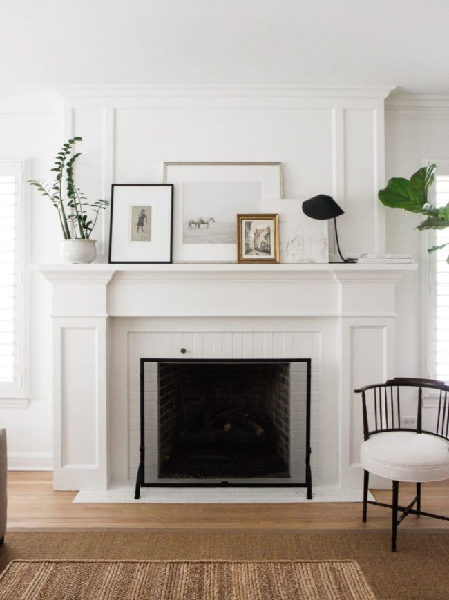 a living room with a fireplace and pictures on the mantel above it, along with a chair