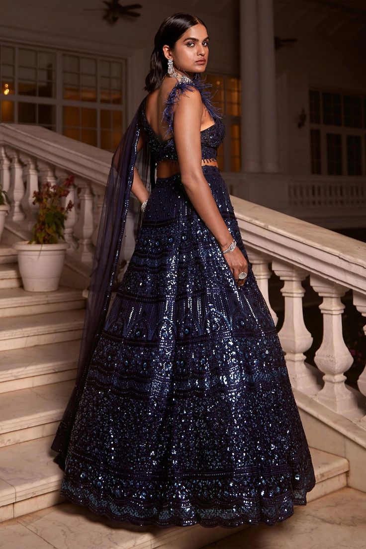 Description:- Get ready to slay in our blue lehenga set crafted in stunning sequin net fabric. Reflect urban elegance in this head-turning ensemble with sequins that sparkle like the night sky, and a statement blouse with dramatic feather-detailing on one sleeve and an attached dupatta with a scalloped border on the other. Style tip: Bring out the diamonds for this one! Pair the outfit with oversized statement earrings or a choker to complement the sequins and add a touch of drama. Fabric : Sequ Sequence Blouse, Indo Western Gown, Saree Petticoat, Full Sleeve Blouse, Saree Jewellery, Statement Blouse, Blue Lehenga, Scalloped Border, Lehenga Skirt