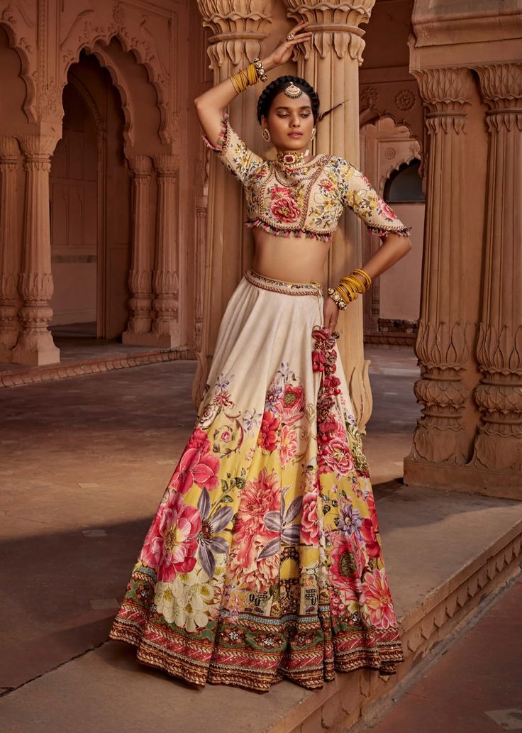 Featuring an elegant interplay of exquisite floral motifs with intricate hand embroidery on the lehenga. It is paired with a meticulously embroidered blouse with intricate thread and hand beadwork on yoke and sleeves and styled with a co-ordinated dupatta. Note: Potli is for styling purposes only Elegant Floral Print Lehenga With Traditional Drape, Elegant Lehenga Saree With Floral Print, Beige Embroidered Reception Set, Beige Set With Intricate Embroidery And Traditional Drape, Elegant Floral Print Choli With Traditional Drape, Elegant Floral Print Traditional Choli, Beige Sets With Intricate Embroidery For Designer Wear, Traditional Cream Hand-embellished Sets, Traditional Hand Embellished Cream Sets