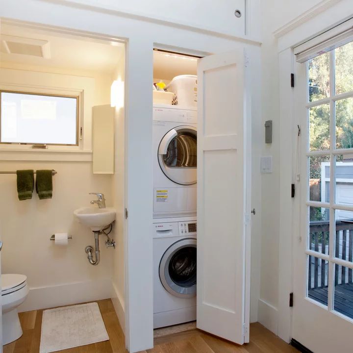 a washer and dryer in a small room next to a door that leads into a bathroom