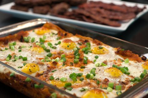 an egg casserole in a pan on a table with crackers and other snacks