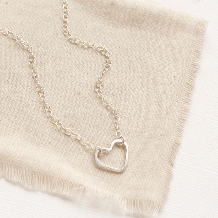 A simple, yet unique necklace to show your love. A simple forged silver heart hangs on silver chain. The heart is attached at two points, so it can change orientation from the side to right side up. Necklace measures 17" - 18 1/2" with lobster clasp and adjustable length chain closure. Small pearls frame the clasp and dangle down the back. Sterling silver. Your jewelry will arrive beautifully gift wrapped in a small box. Multiple items will be combined, unless separate boxes are requested. You will be able to complete this request during check out. If this is a gift being shipped directly to the recipient, you can use the gift box option during check out to include the gift message. If you do not use the gift option, there is no way for me to know these are gifts and your pieces will be wr Open Heart Necklace, Anniversary Necklace, Silver Heart Necklace, Unique Necklace, Open Heart, Unique Necklaces, Hand Forged, Silver Heart, Heart Necklace