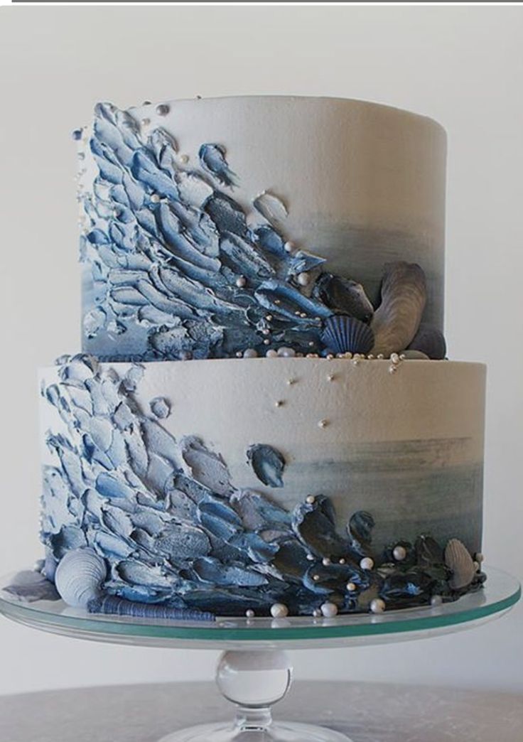 a three tiered cake with blue and white icing on the top, decorated with water droplets