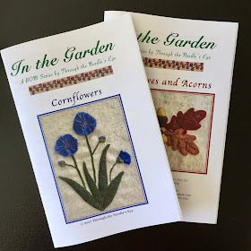 two cross stitch book covers with flowers and acorns in the garden on them